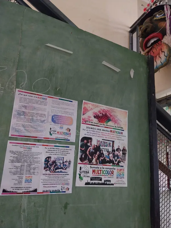 Compañera sosteniendo el afiche del Multicolor frente a una escuela